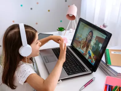 Dete gleda u laptop dok razgovara sa odraslom ženom.